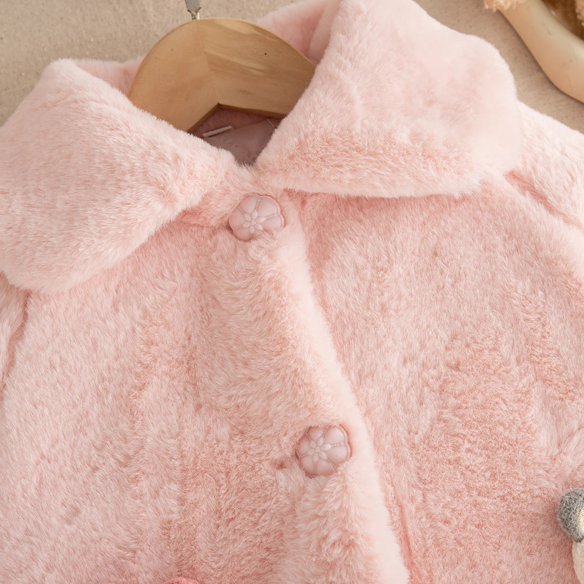 Close-up of the soft faux fur and flower buttons on the baby girl cape coat