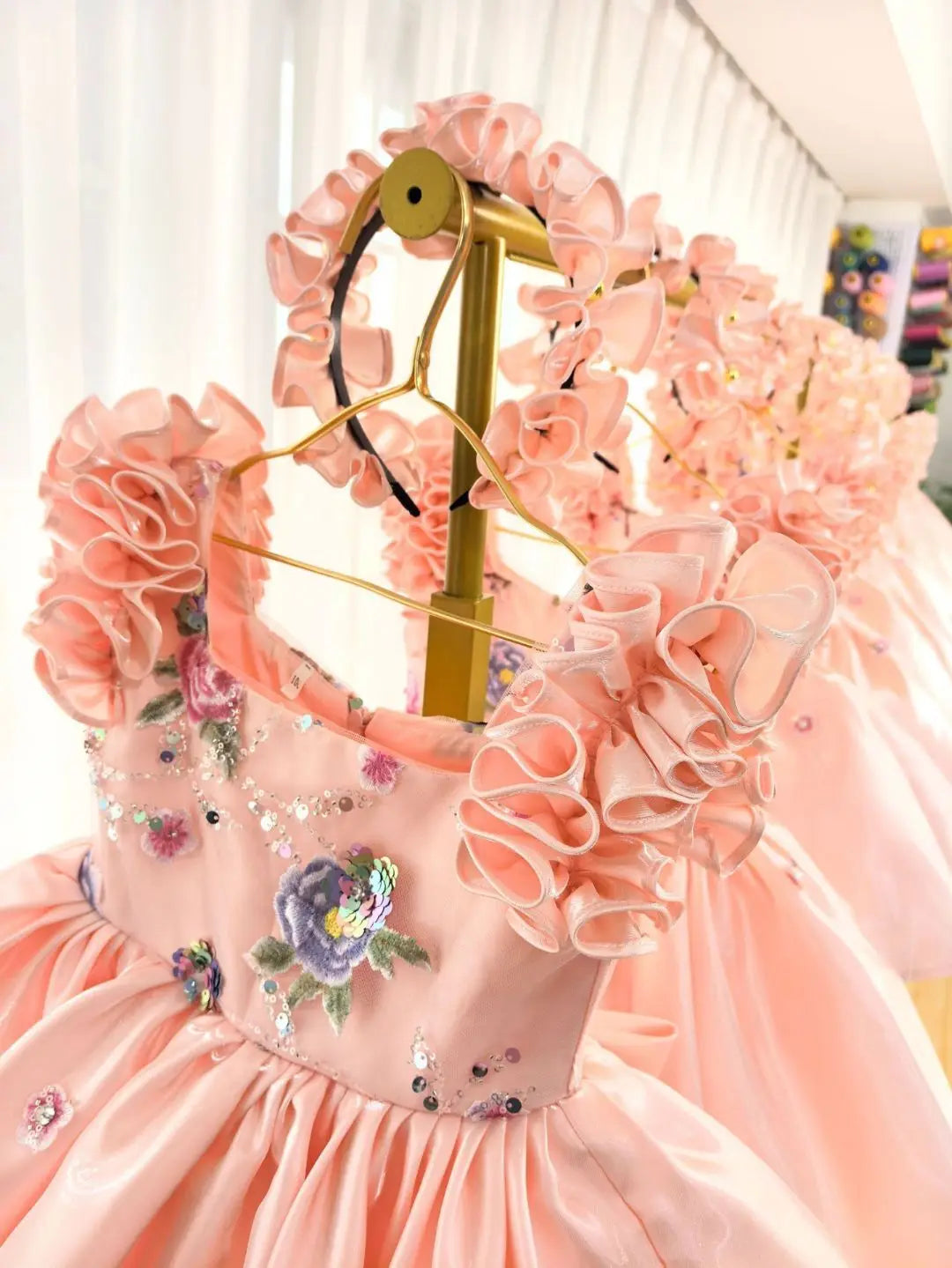 Close-up of the ruffled petal sleeves and beaded floral embroidery on the girls satin dress