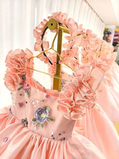 Close-up of the ruffled petal sleeves and beaded floral embroidery on the girls satin dress