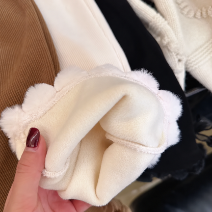 Close-up of warm plush lining and fluffy pom-pom hem on girls corduroy flare pants
