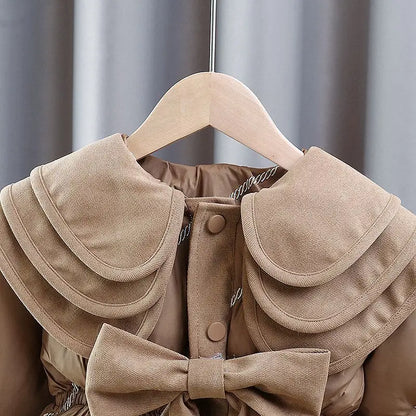 Close-up of the oversized bow on the camel girls puffer coat