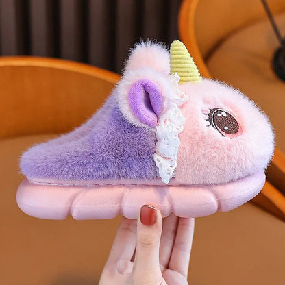 Three pairs of fluffy girls unicorn slippers in pink and lavender on a chair