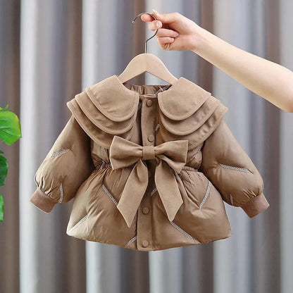 Toddler girl winter puffer coat in camel with oversized bow and three-tier ruffle collar, front view